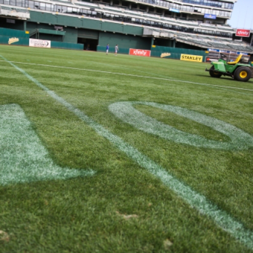A grounds vehicle is seen beyond the washed out football yard numbers on the turf of the Oakland Coliseum on Tuesday, September 22, 2015, prior to a baseball game between the Oakland Athletics and the Texas Rangers. The Oakland Coliseum is the only stadium in America to be shared by an NFL and MLB team.
