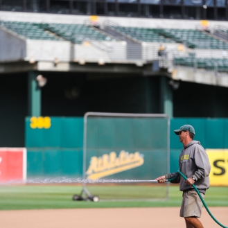 Oakland Coliseum head groundskeeper Clay Wood sprays water onto the dirt near third base at the Oakland Coliseum on Tuesday, September 22, 2015, prior to a baseball game between the Oakland Athletics and the Texas Rangers.